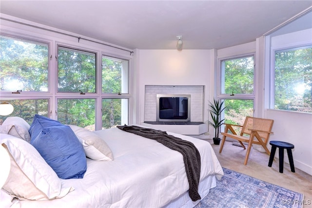 bedroom featuring light carpet, multiple windows, and a brick fireplace