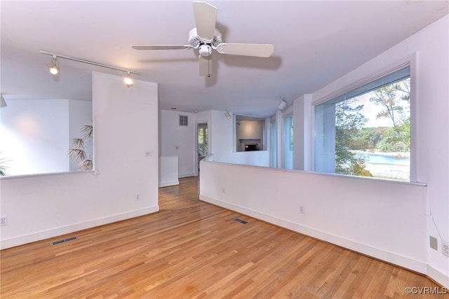 unfurnished living room with track lighting, light hardwood / wood-style flooring, and ceiling fan