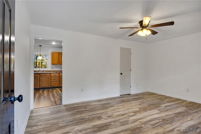 unfurnished room featuring sink, crown molding, wood-type flooring, and ceiling fan