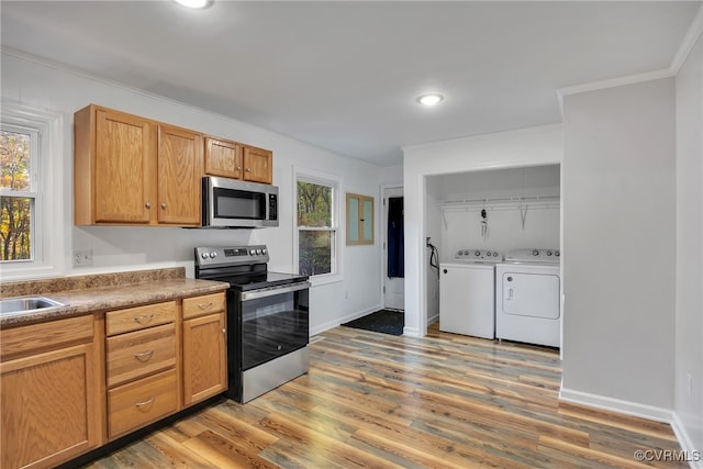 kitchen with independent washer and dryer, a healthy amount of sunlight, appliances with stainless steel finishes, and wood-type flooring