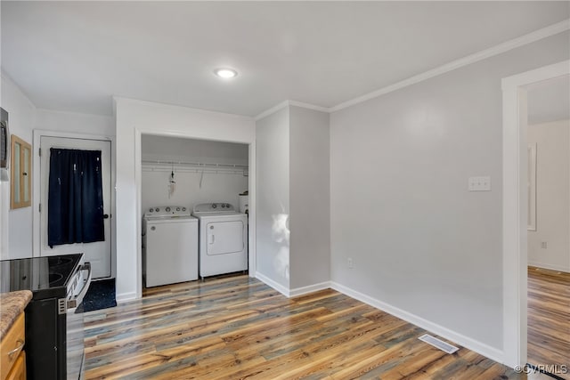 laundry room featuring ornamental molding, hardwood / wood-style flooring, and washing machine and dryer