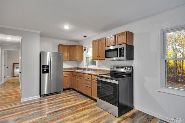 kitchen with sink, light hardwood / wood-style floors, stainless steel appliances, pendant lighting, and ornamental molding