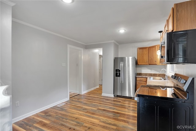 kitchen with sink, range, hardwood / wood-style flooring, ornamental molding, and stainless steel refrigerator with ice dispenser