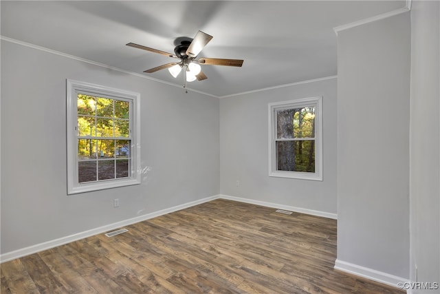 spare room with a wealth of natural light, crown molding, ceiling fan, and dark hardwood / wood-style flooring