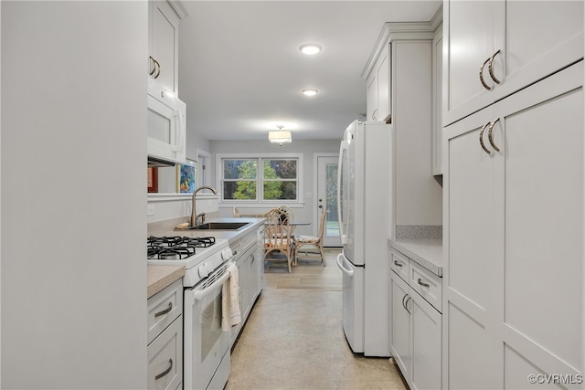 kitchen with white appliances, light hardwood / wood-style flooring, sink, and white cabinets