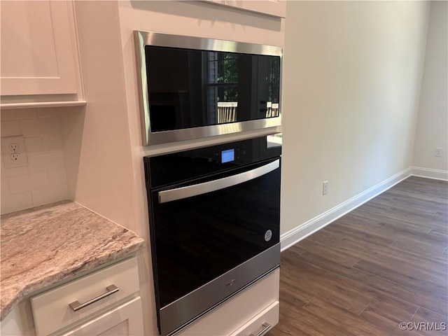 2050 Swiss Ln, Hayes, VA 23072 - kitchen with stainless steel microwave, wall oven, white cabinetry, dark wood-type flooring, and light stone counters