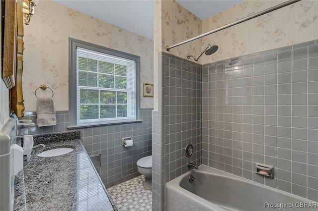 full bathroom featuring vanity, toilet, tile walls, and tiled shower / bath