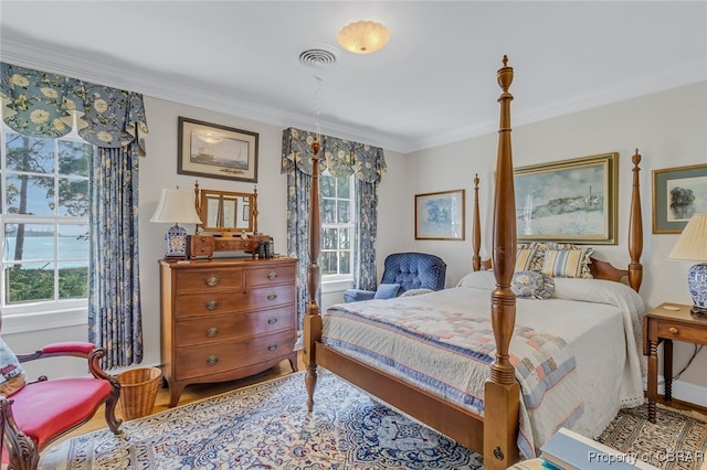 bedroom featuring hardwood / wood-style flooring, ornamental molding, and multiple windows