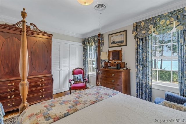 bedroom featuring hardwood / wood-style floors, crown molding, a water view, and a closet