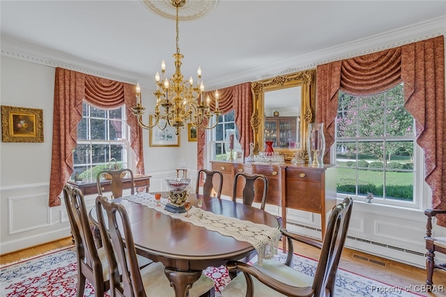 dining area featuring crown molding, a chandelier, and light wood-type flooring