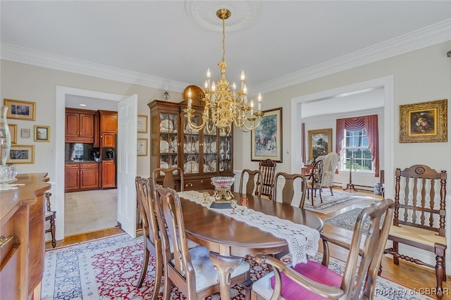 dining space featuring crown molding, light hardwood / wood-style flooring, and a chandelier