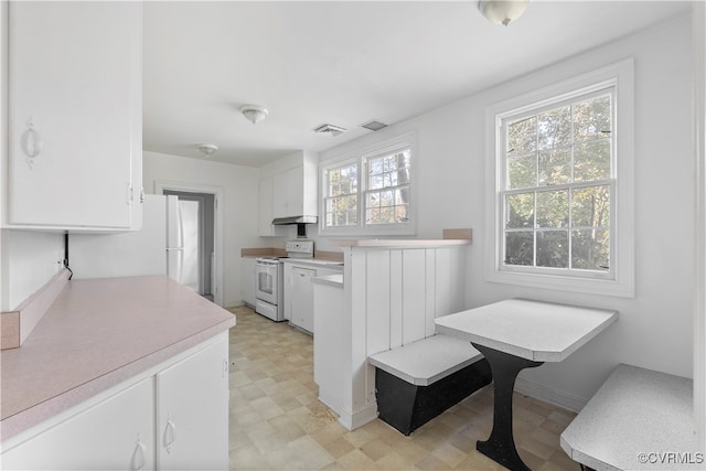 kitchen with white cabinets, kitchen peninsula, and white appliances