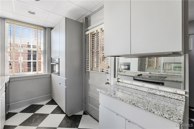 kitchen featuring white cabinets, a wealth of natural light, and light stone countertops