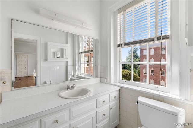 bathroom with toilet, tile walls, and vanity