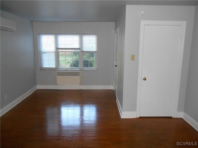 unfurnished room featuring a wall mounted AC and dark hardwood / wood-style flooring