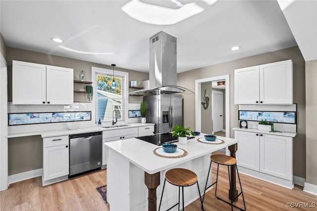 kitchen with pendant lighting, island exhaust hood, white cabinetry, and stainless steel appliances