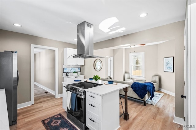 kitchen with stainless steel appliances, island range hood, ceiling fan, a center island, and white cabinetry