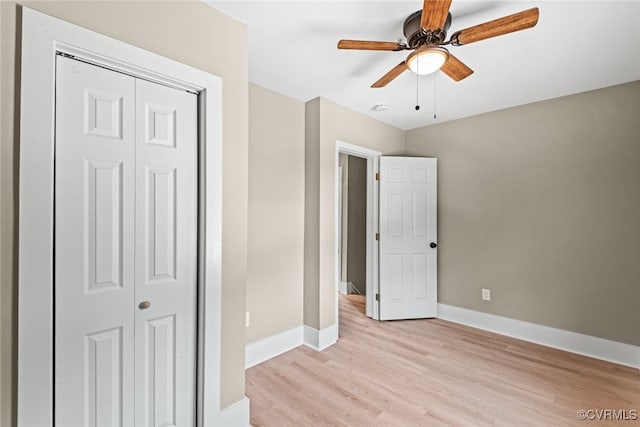 unfurnished bedroom featuring ceiling fan, light wood-type flooring, and a closet