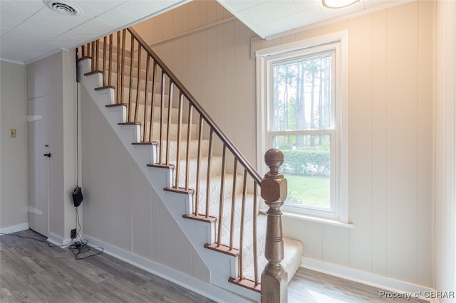 stairway with ornamental molding, wood walls, and wood-type flooring