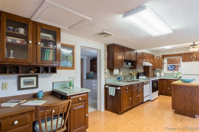 kitchen with a textured ceiling, sink, light wood-type flooring, and white appliances