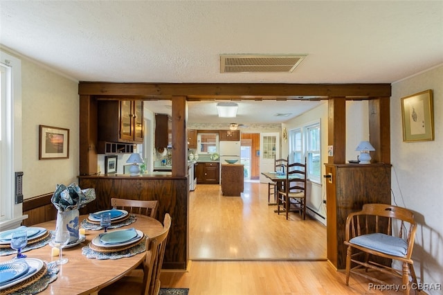 dining space with crown molding, a textured ceiling, and light wood-type flooring