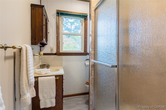 bathroom with vanity, hardwood / wood-style floors, a shower with shower door, and toilet