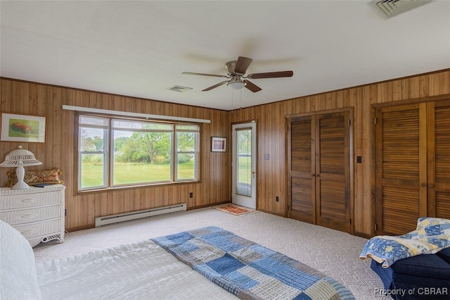 bedroom featuring ceiling fan, a baseboard radiator, wooden walls, and light colored carpet