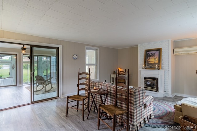 interior space featuring light hardwood / wood-style floors, a brick fireplace, and a wall unit AC