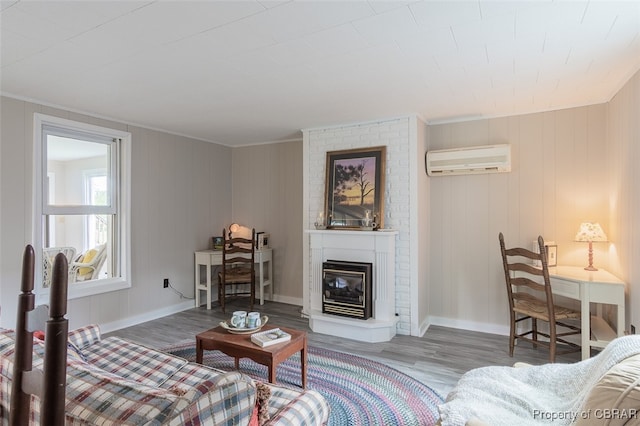 living room featuring a wall unit AC, hardwood / wood-style flooring, wooden walls, a large fireplace, and crown molding