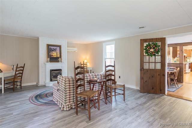 dining area featuring a wall mounted air conditioner, light hardwood / wood-style flooring, a fireplace, and crown molding