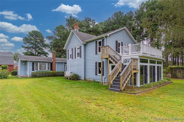 rear view of house with a wooden deck and a lawn