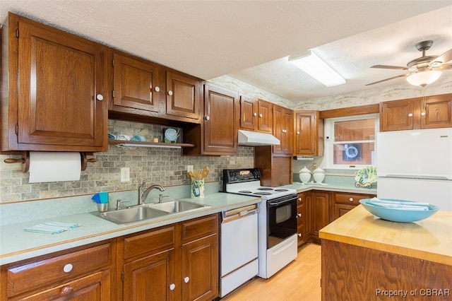 kitchen featuring white appliances, sink, light wood-type flooring, butcher block counters, and a textured ceiling