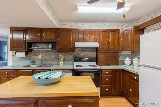 kitchen with a textured ceiling, butcher block counters, sink, and white appliances