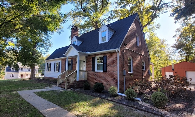 cape cod-style house with a garage, a front lawn, and an outbuilding