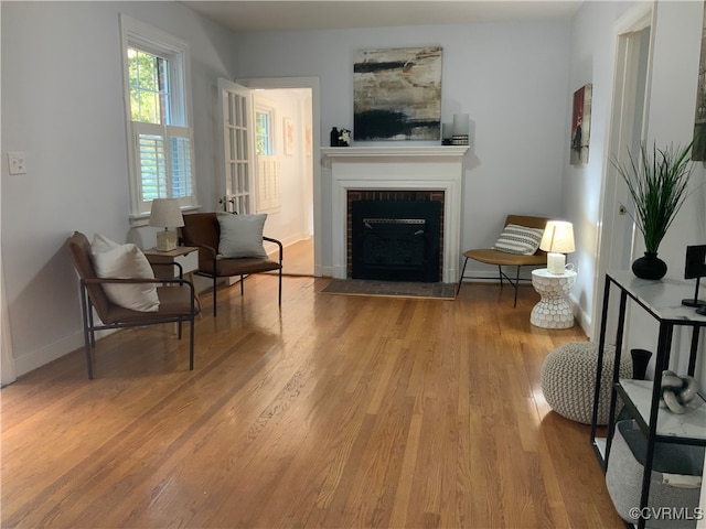 sitting room with light hardwood / wood-style flooring and a brick fireplace