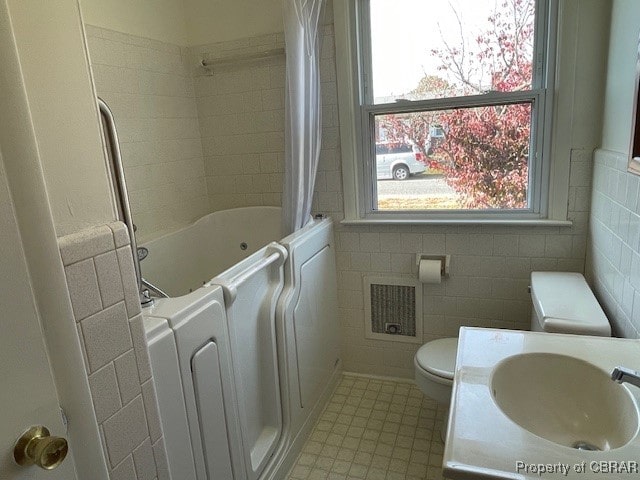 full bathroom with toilet, shower / bath combo with shower curtain, sink, and tile walls