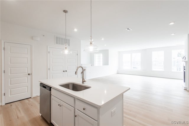 kitchen with hanging light fixtures, a center island with sink, stainless steel dishwasher, light wood-type flooring, and sink