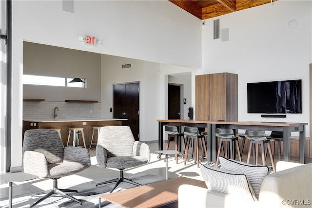 living room with sink, beam ceiling, and a high ceiling