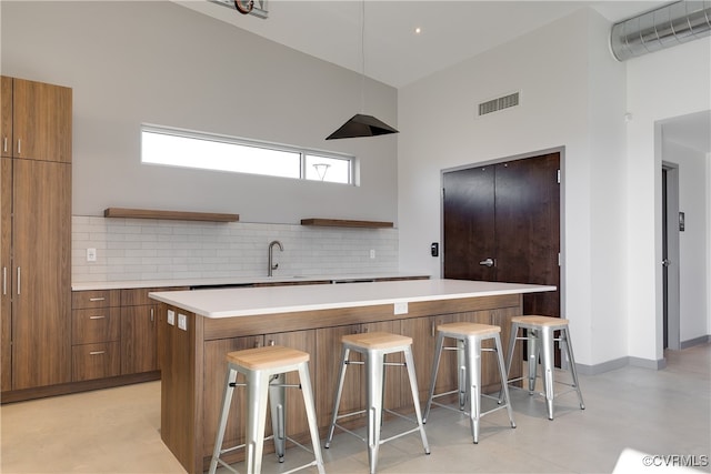 kitchen featuring sink, a center island, tasteful backsplash, and a breakfast bar area