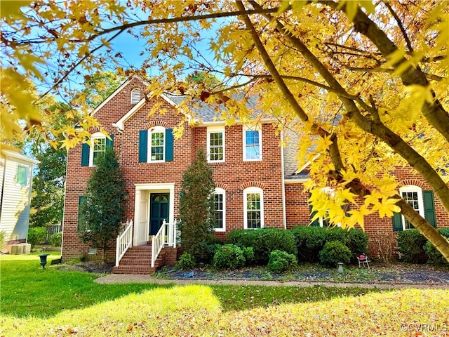 view of front of home with central air condition unit and a front lawn