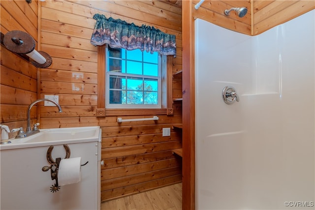 bathroom with wood-type flooring, sink, and wooden walls