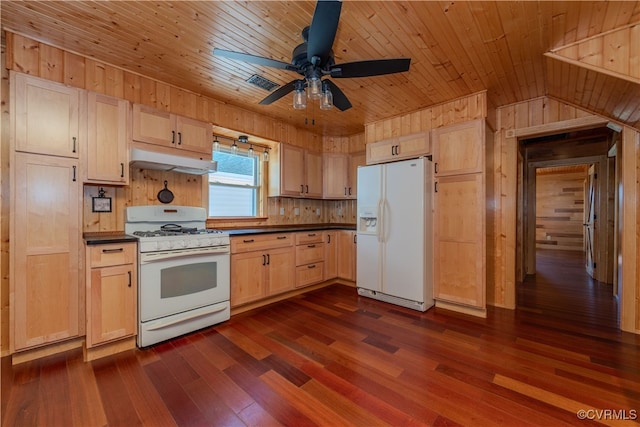 kitchen featuring light brown cabinetry, dark hardwood / wood-style floors, white appliances, and wood walls