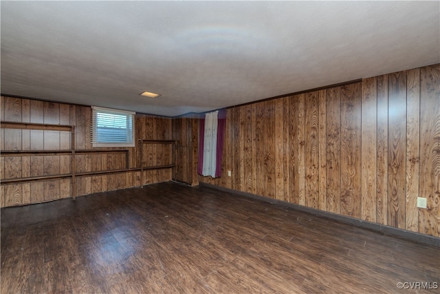 spare room featuring wood walls and dark hardwood / wood-style flooring