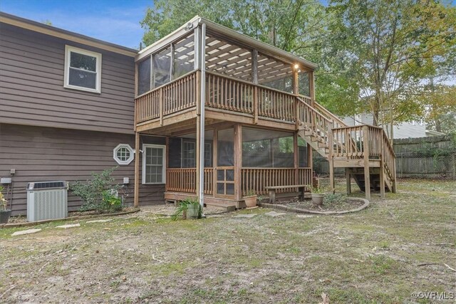 rear view of property with a wooden deck, a lawn, a sunroom, and central AC unit