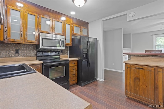 kitchen with black appliances, dark wood-type flooring, sink, and backsplash