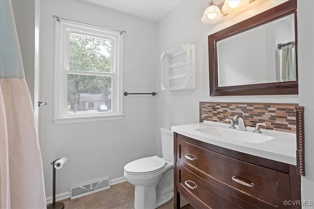 bathroom featuring vanity, toilet, and backsplash