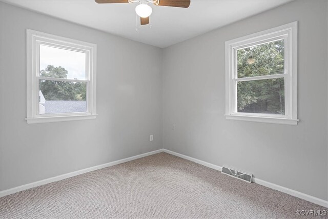 carpeted spare room with a wealth of natural light and ceiling fan