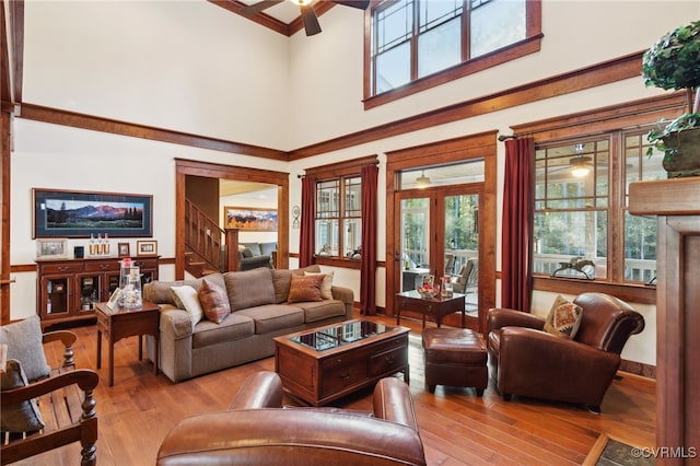 living room with french doors, a towering ceiling, a wealth of natural light, and light wood-type flooring