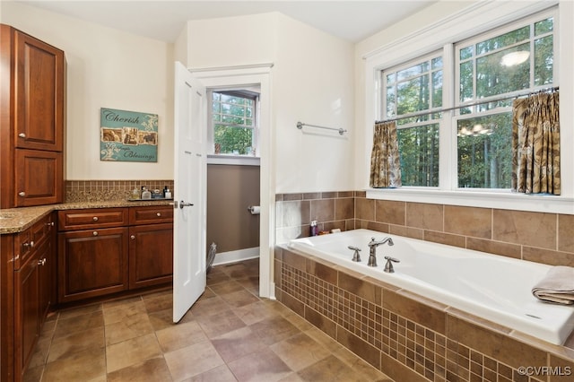 bathroom with vanity, a relaxing tiled tub, tile patterned floors, and a wealth of natural light