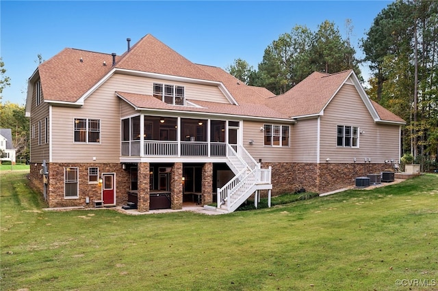 rear view of house featuring central air condition unit, a lawn, and a sunroom